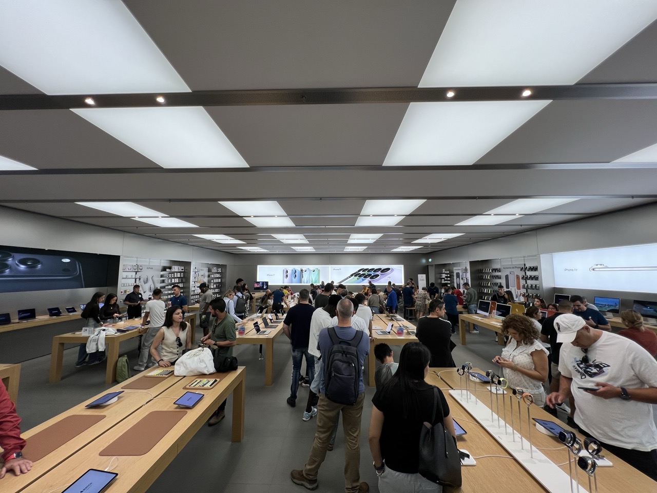 Des gens font la queue dans un Apple Store, avec des affiches d’iPhone 17 en arrière-plan